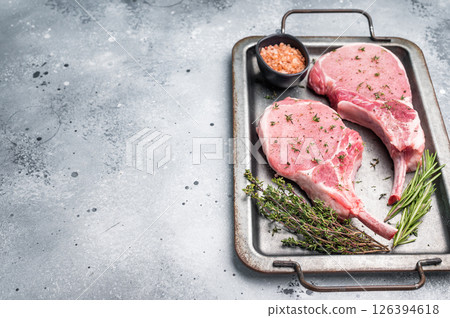 Stunning uncooked pork Tomahawk chop steak, promising tenderness and flavor in every bite when grilled or roasted. grey background. top view Stunning uncooked pork Tomahawk chop steak, promising tenderness and flavor in every bite when grilled or roasted. grey background. top view 126394618