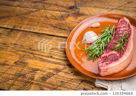 Raw sirloin beef steak, featuring a vibrant hue and well defined grain. wooden background. top view 126394668
