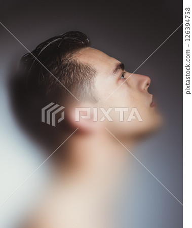 Conceptual collage. Young man in profile lit from below, eyes turned upward in soft gradient, expressing hope and concentration. Conceptual collage. Young man in profile lit from below, eyes turned upward in soft gradient, expressing hope and concentration. 126394758