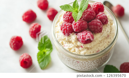 A jar of creamy chia pudding topped with fresh raspberries and mint leaves, placed on a clean white table with soft natural light, concept of healthy eating A jar of creamy chia pudding topped with fresh raspberries and mint leaves, placed on a clean white table with soft natural light, concept of healthy eating 126395670