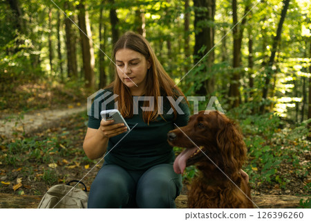 Woman Sitting on a Log with Her Dog in the Forest Woman Sitting on a Log with Her Dog in the Forest 126396260