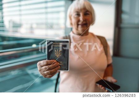 Senior woman holding passport and smartphone at airport check-in 126396283
