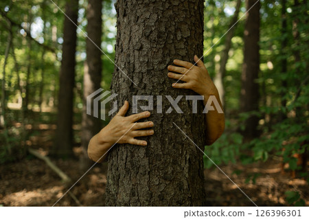 Person Hugging Tree with Open Hands in Forest Showing Deep Connection to Nature and Earth 126396301