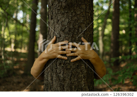 Person Hugging Tree with Open Hands in Forest Showing Deep Connection to Nature and Earth 126396302