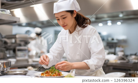 A young female chef finishing up a dish in the kitchen 126396324