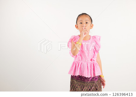 Portrait Thailand kid girl smiling traditional Thai dress costume making finger on lips mouth silent quiet gesture, studio isolated white background, kindergarten child marking silence for stop quiet Portrait Thailand kid girl smiling traditional Thai dress costume making finger on lips mouth silent quiet gesture, studio isolated white background, kindergarten child marking silence for stop quiet 126396413