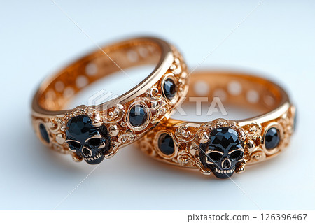 Pair of gold wedding rings with a skull pattern on a white background. Original style. 126396467