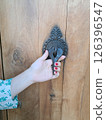 Woman hand holding a vintage doorknob on wooden door 126396547