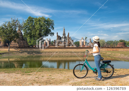 single tourist with a bicycle for ride to explore well-maintained ruins of old temple and statue of ancient buddha in Sukhothai Historical Park route. famous landmark place for Thailand sight seeing single tourist with a bicycle for ride to explore well-maintained ruins of old temple and statue of ancient buddha in Sukhothai Historical Park route. famous landmark place for Thailand sight seeing 126396789