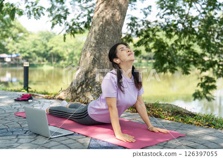 Wellness and Mindfulness. Woman practicing yoga outdoors by the lake. 126397055