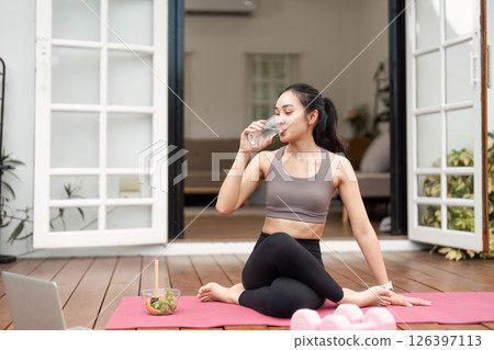 Yoga and Self-Care. Young woman sipping water during yoga practice at home. 126397113