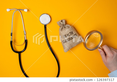 Health insurance concept. Contract that helps cover medical expenses by paying for or reimbursing healthcare costs. Bag of money, stethoscope and magnifying glass in female hands 126397317
