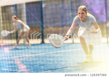 Woman with racket on court playing paddle in the background of sunshine Woman with racket on court playing paddle in the background of sunshine 126397360