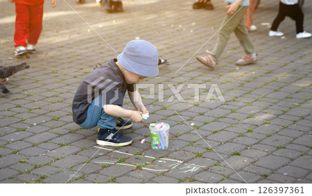 Little toddler boy four old draws with crayons in the park on tiles. Playtime for children. Children's games. Selective focus 126397361