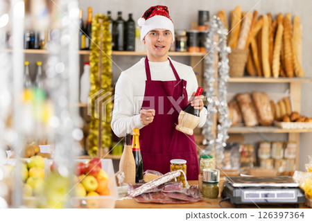 Young salesman is offering products for New Year party in grocery store 126397364