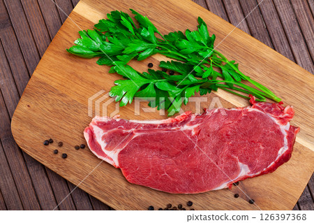 Piece of raw boneless beef with seasonings and greens 126397368