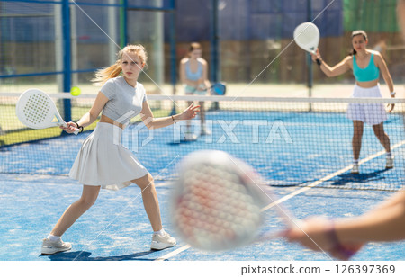 Young woman playing paddle tennis against team of women 126397369