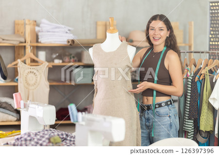 Female fashion designer sewing dress and testing it on mannequin 126397396