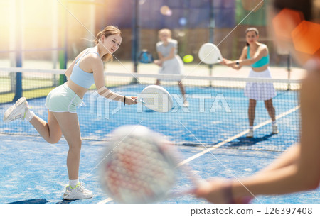 Young woman playing paddle tennis against team of women 126397408