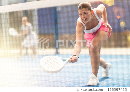 Woman with racket on court playing paddle in the background of sunshine Woman with racket on court playing paddle in the background of sunshine 126397433