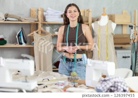 Young female dressmaker welcoming clients in sewing workshop Young female dressmaker welcoming clients in sewing workshop 126397455