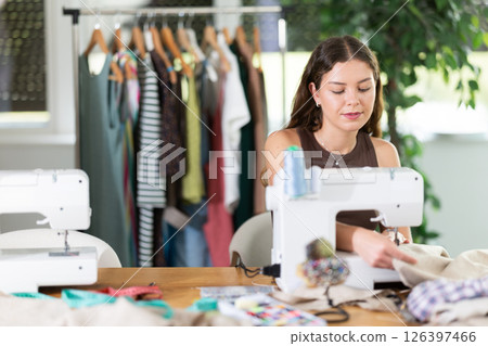 Young female dressmaker working with sewing-machine in tailor's workshop 126397466