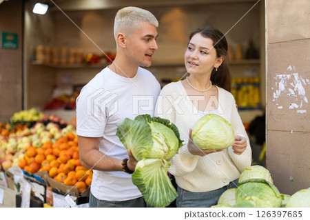 Married couple near vegetable stand in store choose cabbage Married couple near vegetable stand in store choose cabbage 126397685