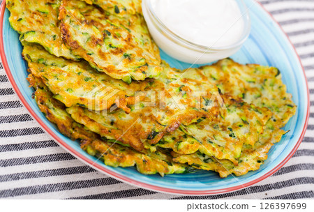 Zucchini pancakes with sour cream 126397699
