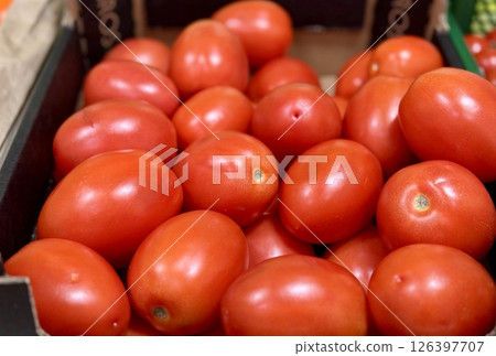 A vibrant display of ripe cherry tomatoes stacked neatly in a green basket at a bustling local market. Close-up. A vibrant display of ripe cherry tomatoes stacked neatly in a green basket at a bustling local market. Close-up. 126397707