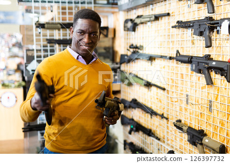 Portrait of african american man choice pneumatic gun in airsoft market 126397732