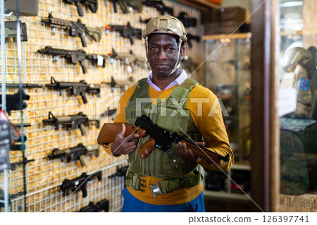 African american guy in military equipment with weapon in military shop 126397741