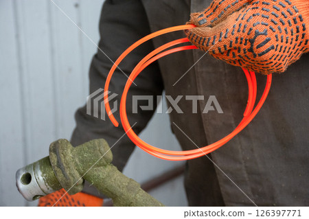 Gardening worker preparing hand trimmer for grass mowing, garden maintenance 126397771