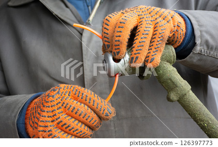 Male hands in gloves setting up manual lawn mower to clean grass 126397773