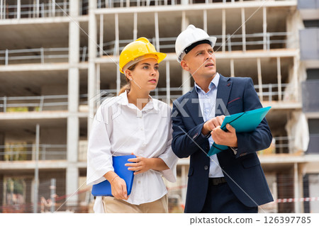 Two young successful architects on the construction site, discuss the construction plan Two young successful architects on the construction site, discuss the construction plan 126397785