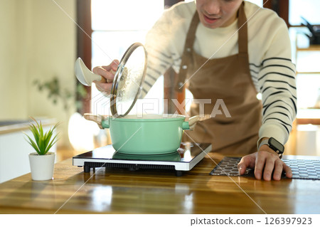 Happy Asian man cooking at home with fresh ingredients Happy Asian man cooking at home with fresh ingredients 126397923