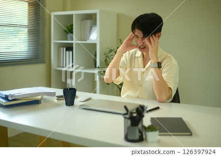 Stressed young man overwhelmed with work at home office Stressed young man overwhelmed with work at home office 126397924