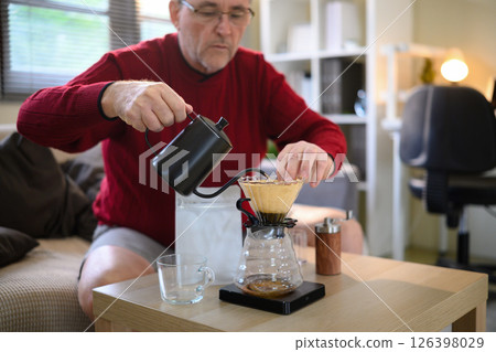 Senior man making fresh pour over coffee at home using a gooseneck kettle and glass dripper 126398029