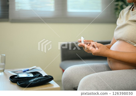 Close up of pregnant woman checking her blood sugar at home 126398030