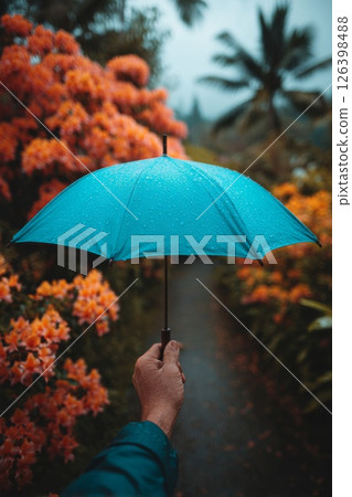 Person Holding Teal Umbrella in a Rainy Garden 126398488