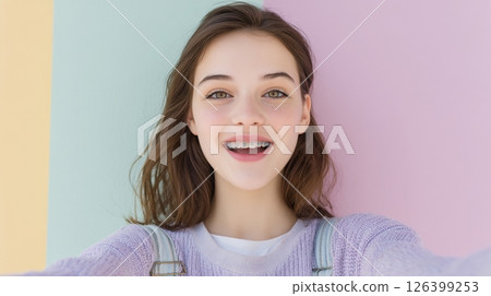 Cheerful teen captures a playful selfie highlighting her colorful metal braces in bright daylight 126399253