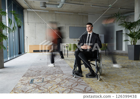 A businessman in a wheelchair navigating through a busy office, surrounded by his colleagues who are actively engaged in their work and collaboration A businessman in a wheelchair navigating through a busy office, surrounded by his colleagues who are actively engaged in their work and collaboration 126399438