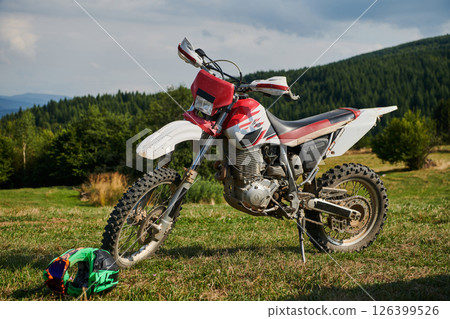 A professional motocross standing poised in a meadow, fully geared up and ready for a competitive race, with the anticipation of adrenaline-fueled excitement in the air. 126399526