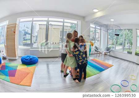 A child hugging a teacher in a modern kindergarten 126399530