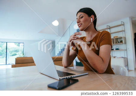Woman sitting in living room using laptop looking at cam talk by video call with business friend relatives, head shot. Job interview answering questions Woman sitting in living room using laptop looking at cam talk by video call with business friend relatives, head shot. Job interview answering questions 126399533