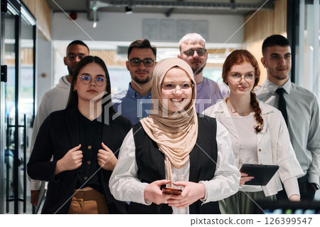A group of business professionals standing together, taking a well-deserved break from their busy workday, showcasing camaraderie, teamwork, and a moment of relaxation in their dynamic workplace 126399547