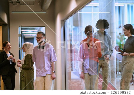 Amidst the modern glass walls of a startup office, a diverse group of colleagues, including an African American man, engage in a coffee-fueled discussion, exemplifying collaboration and innovation in 126399582