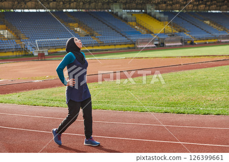 A Muslim woman with a burqa, an Islamic sportswoman resting after a vigorous training session on the marathon course. A hijab woman is preparing for a marathon competition 126399661
