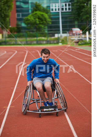 A person athlete with disability in a wheelchair racing on an outdoor track. A person athlete with disability in a wheelchair racing on an outdoor track. 126399692