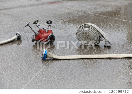 Coiled Fire Hose Ready for Action on the Ground Coiled Fire Hose Ready for Action on the Ground 126399712