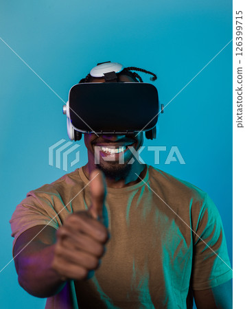 African American man wearing virtual reality glasses expresses satisfaction and impressed delight, gesturing with his hand pointed upward, while standing isolated against a vibrant yellow background African American man wearing virtual reality glasses expresses satisfaction and impressed delight, gesturing with his hand pointed upward, while standing isolated against a vibrant yellow background 126399715